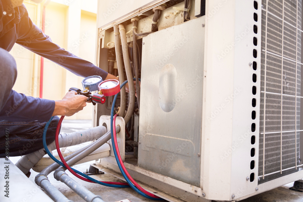 Technician is checking air conditioner ,measuring equipment for